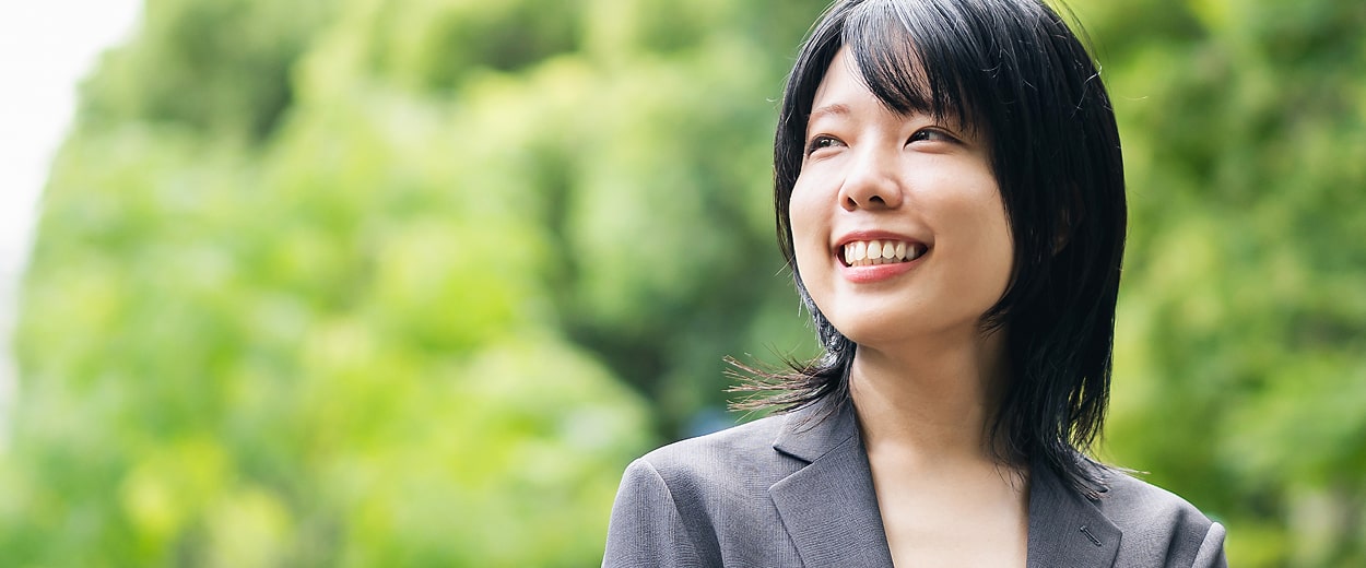 屋外を見上げて笑顔を見せる女性社員